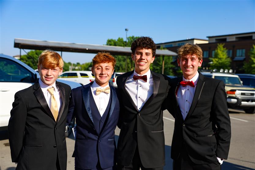 A group of young men wearing tuxedos stands together